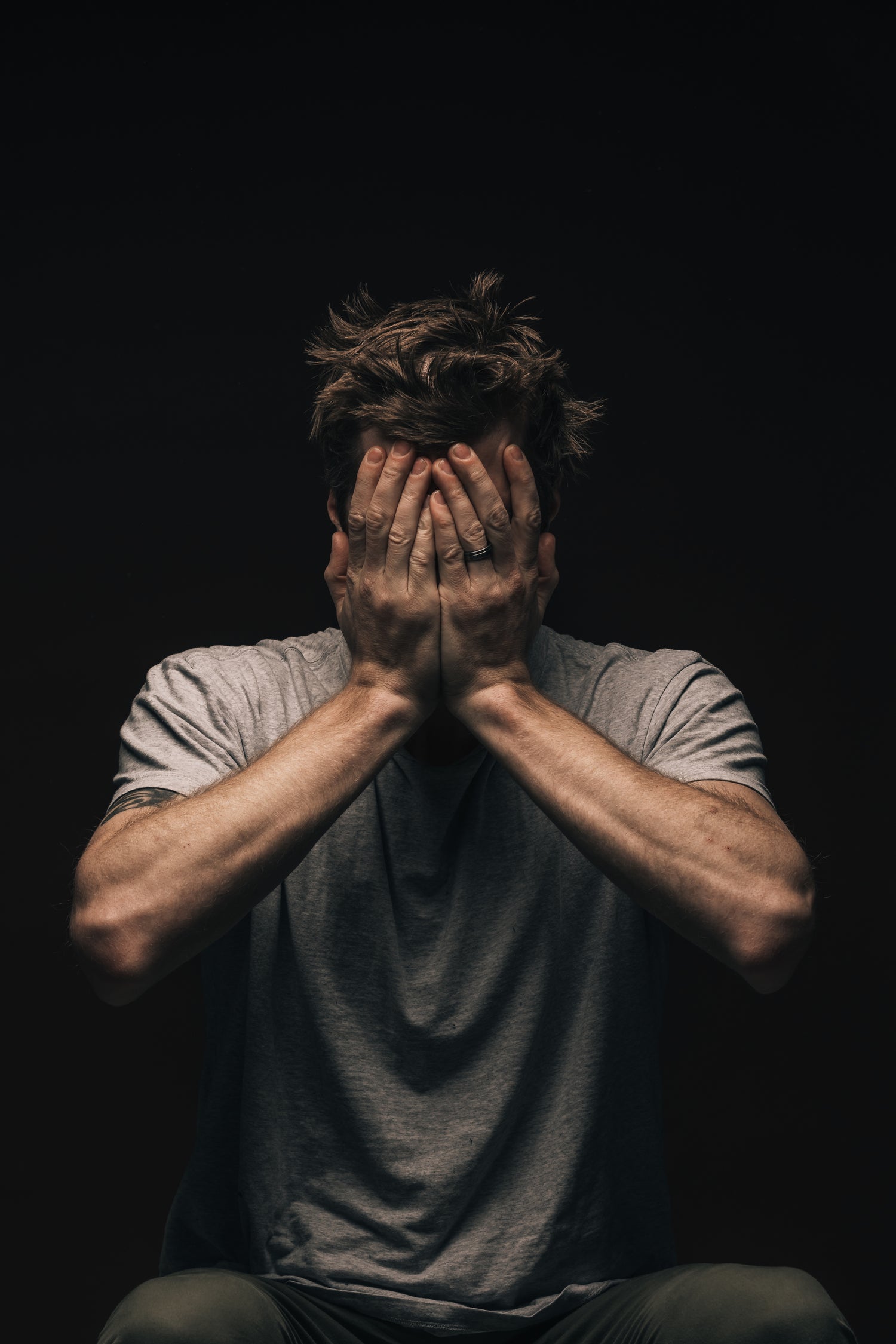 Footballer covering his face with hands, feeling defeated on game day after not starting, reflecting the emotional struggles athletes face in their journey to building an elite mindset with Elite Footy Mentality